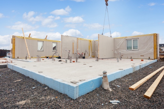 Homeowner building pressure-treated lumber gazebo in brick patio backyard.